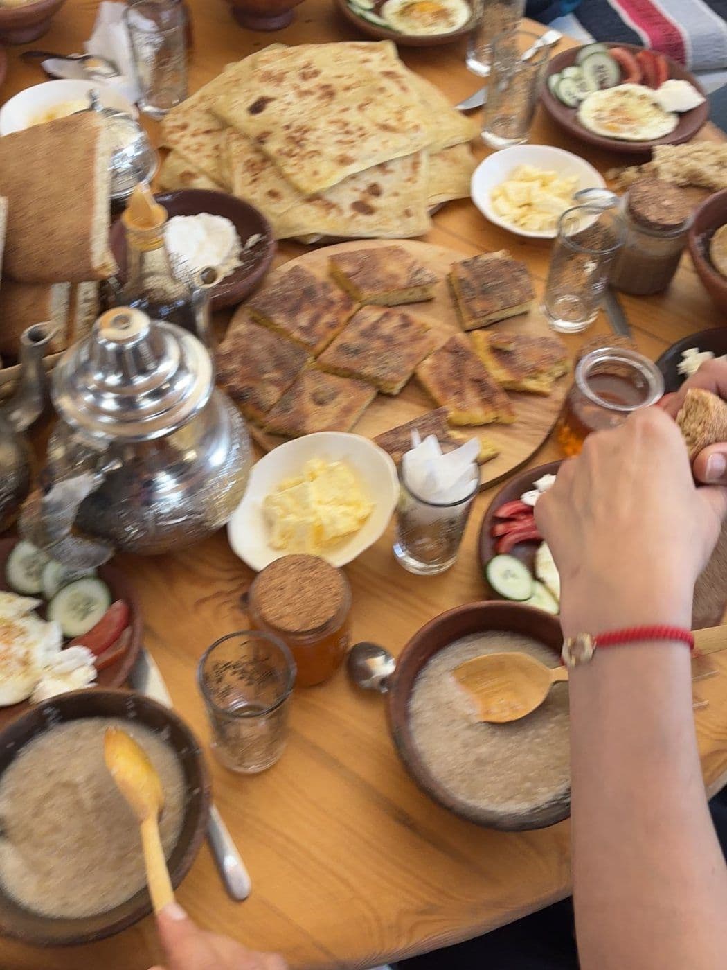 Un petit-déjeuner marocain servi sur une table devant un mur de zellige